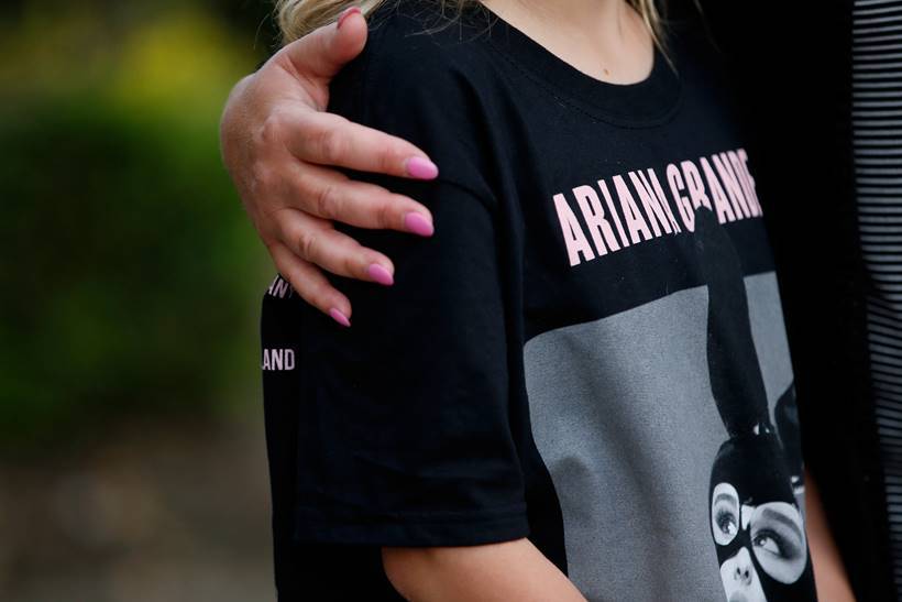 A youngster wearing a t-shirt showing U.S. singer Ariana Grande talks to the media near the Manchester Arena in Manchester